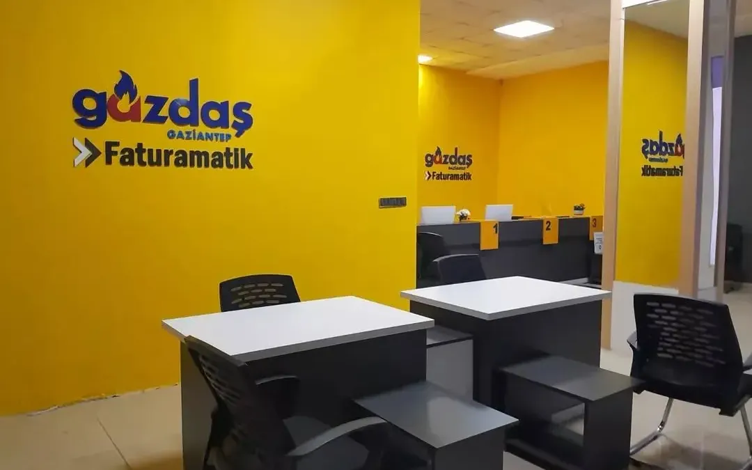 Kurumsal renklerle uygulanmış ofis iç mekânı: duvarda kabartma logo, banko ve mobilya